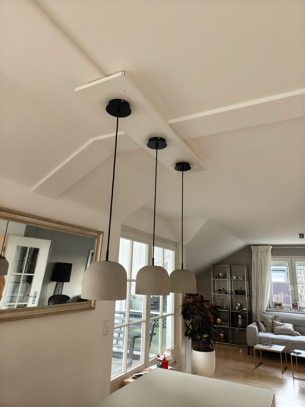 Drei graue Pendelleuchten in einer Reihe an der Decke