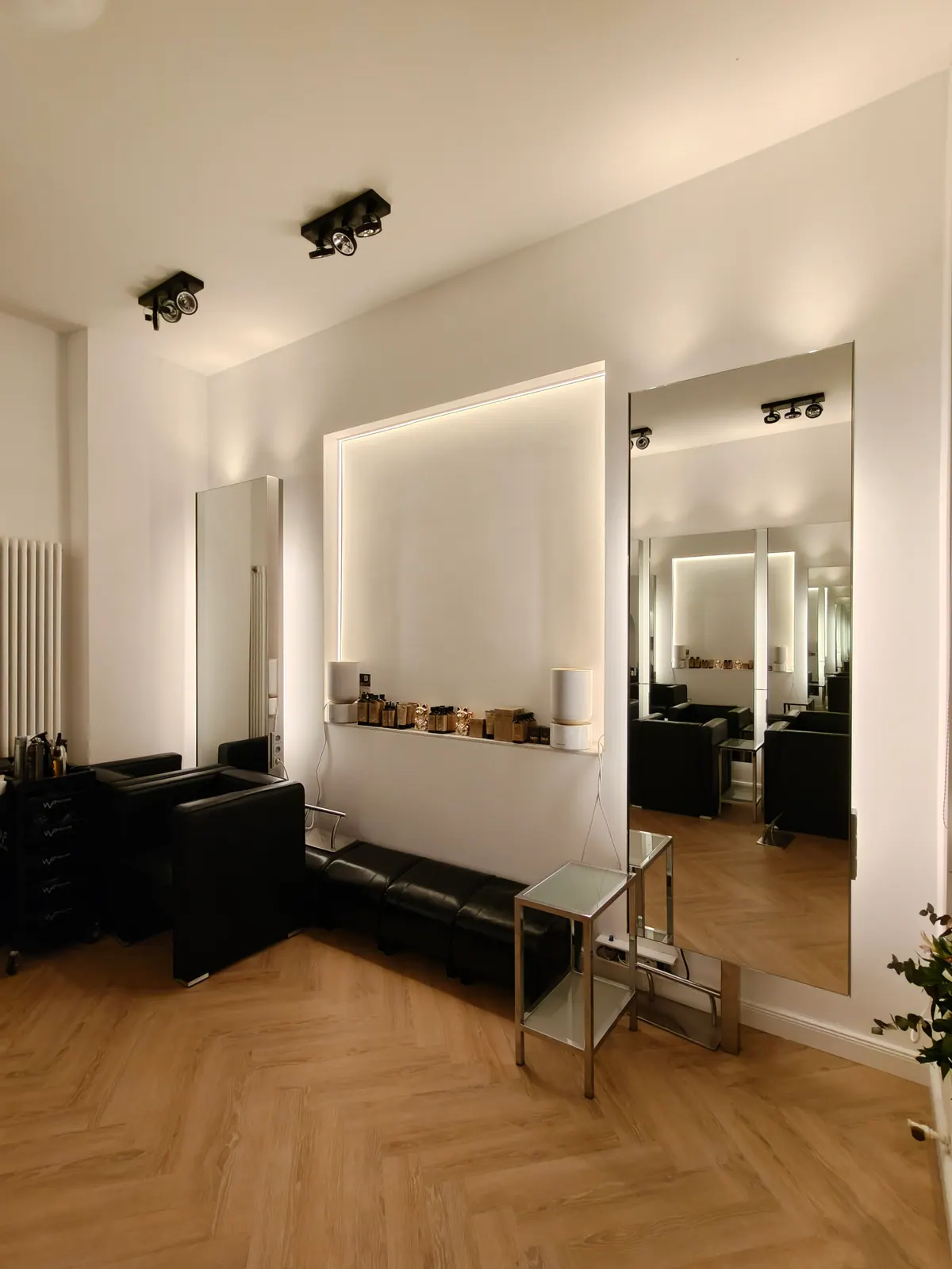 Friseursalon mit schwarzen Deckenspots und hinterleuchteter Wandnische
